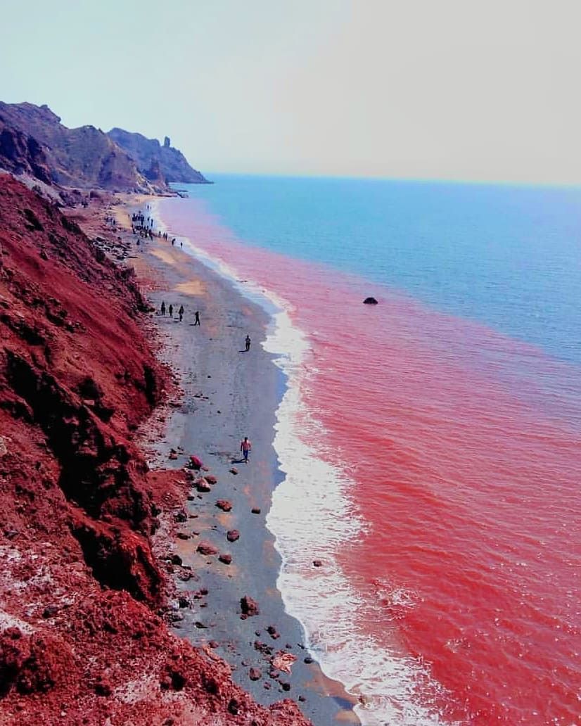Red mineral cliffs beside blue coastal water